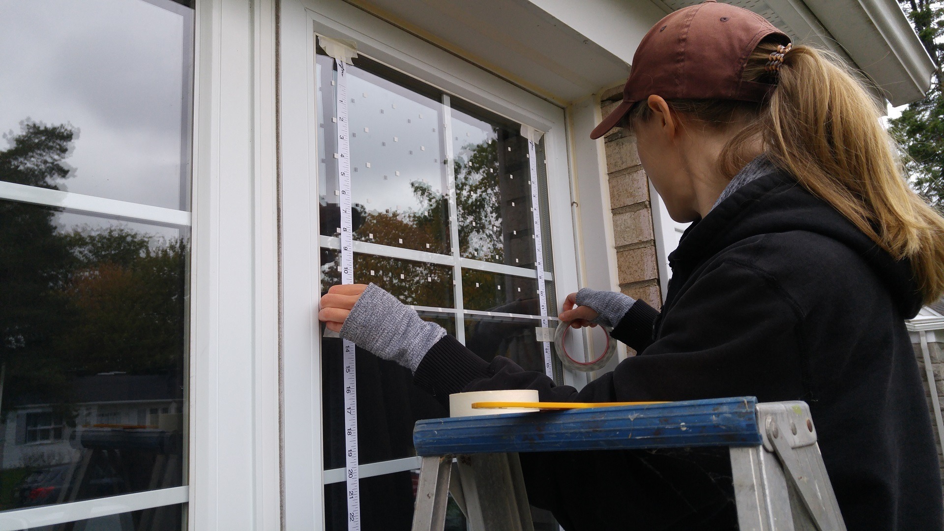 A woman installing decals on her windows for preventing bird-window collisions