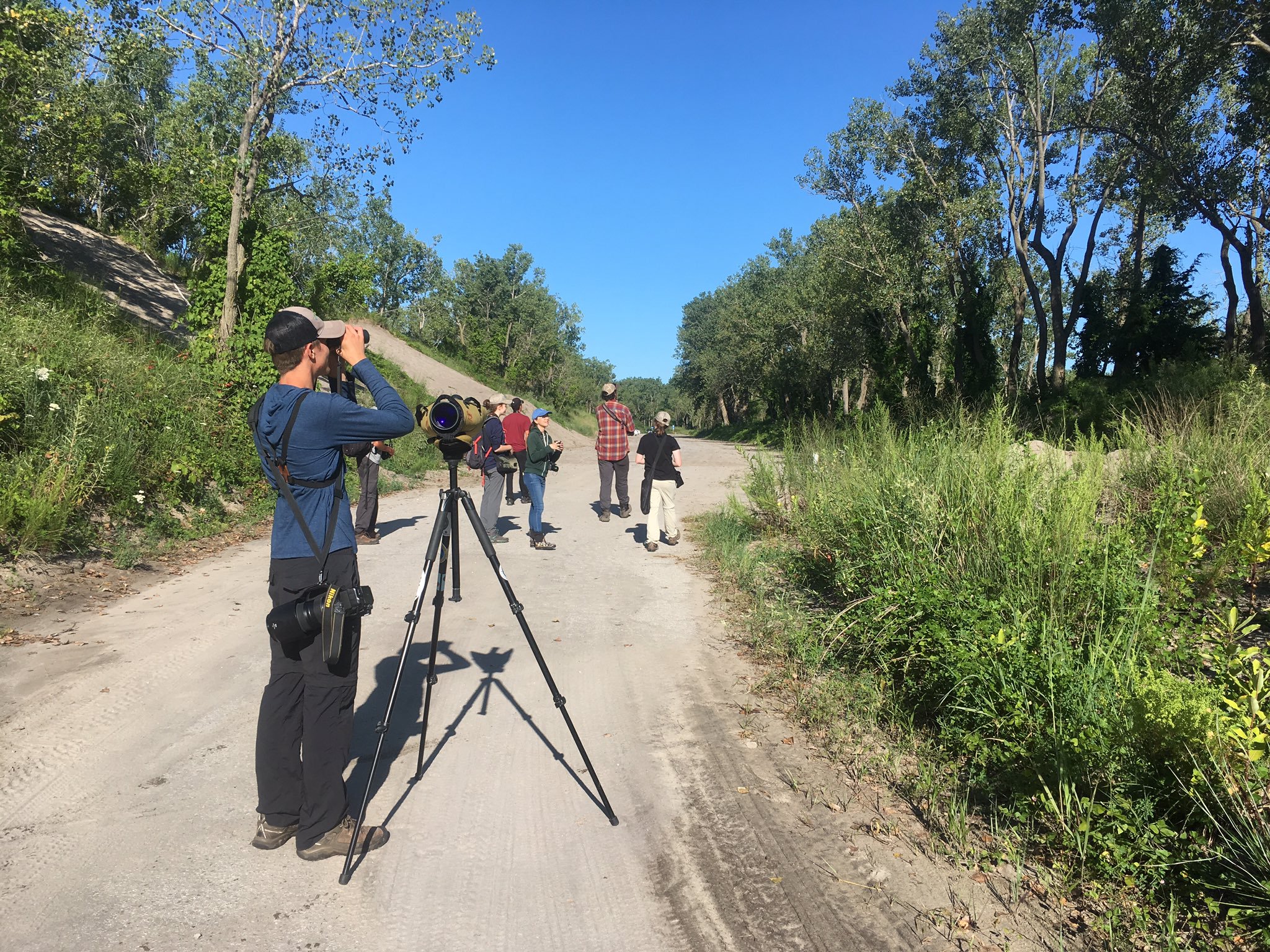A group of young birders watching birds on a dirt road