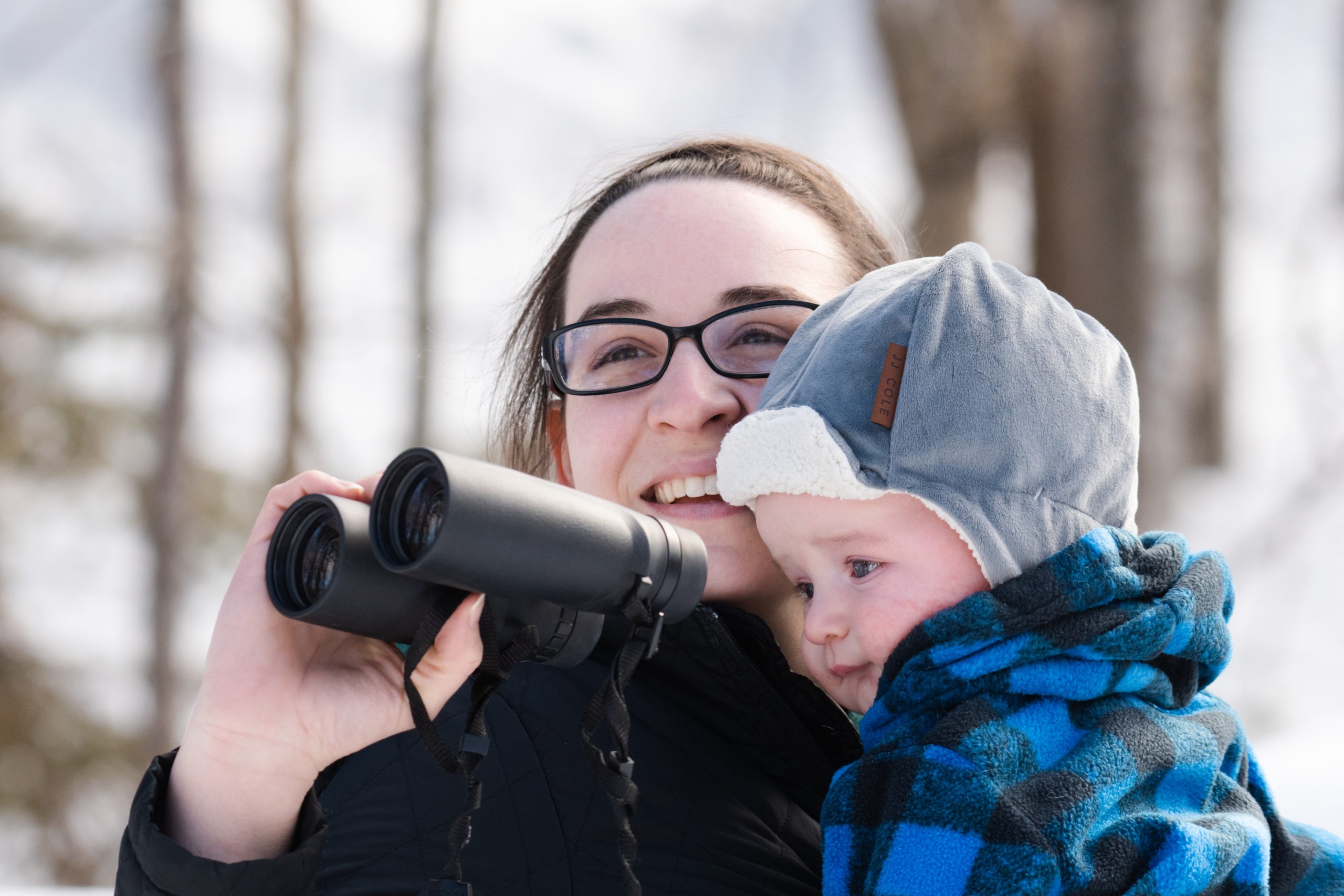 A woman and young child watch birds with binoculars.
